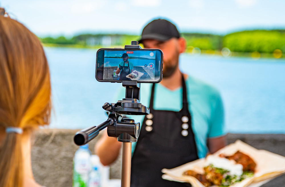 man chef gives an interview for a video blogger. videographer is filming the cook's story about cooking. outdoor man chef gives an interview for a video blogger. videographer is filming the cook's story about cooking. outdoor